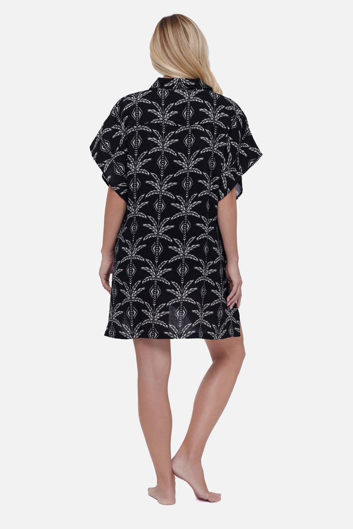 Woman turned away wearing a black and white palm leaf printed swim cover up shirt