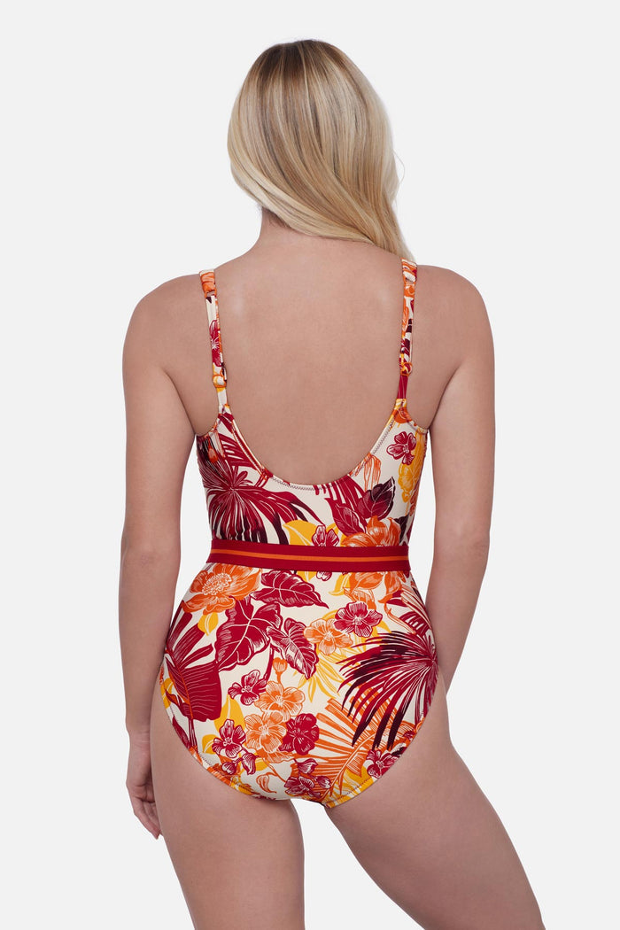 Woman turned away wearing a multicolored palm leaf printed one-piece swimsuit with a belt