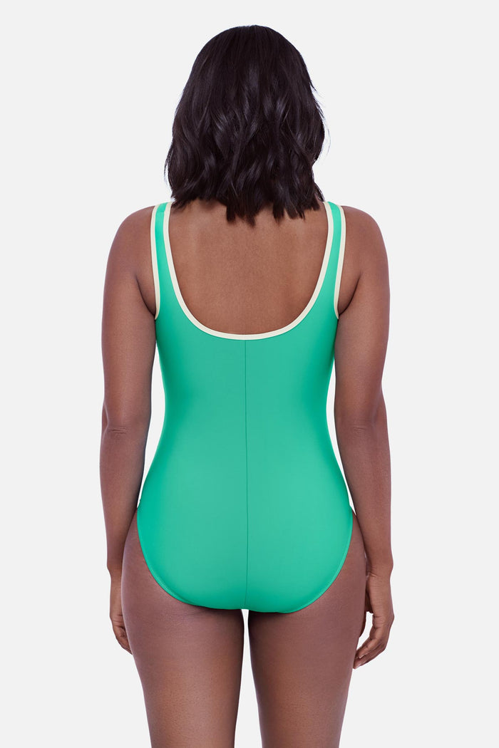 Woman faced away wearing a seafoam green one-piece swimsuit with white piping on the edges