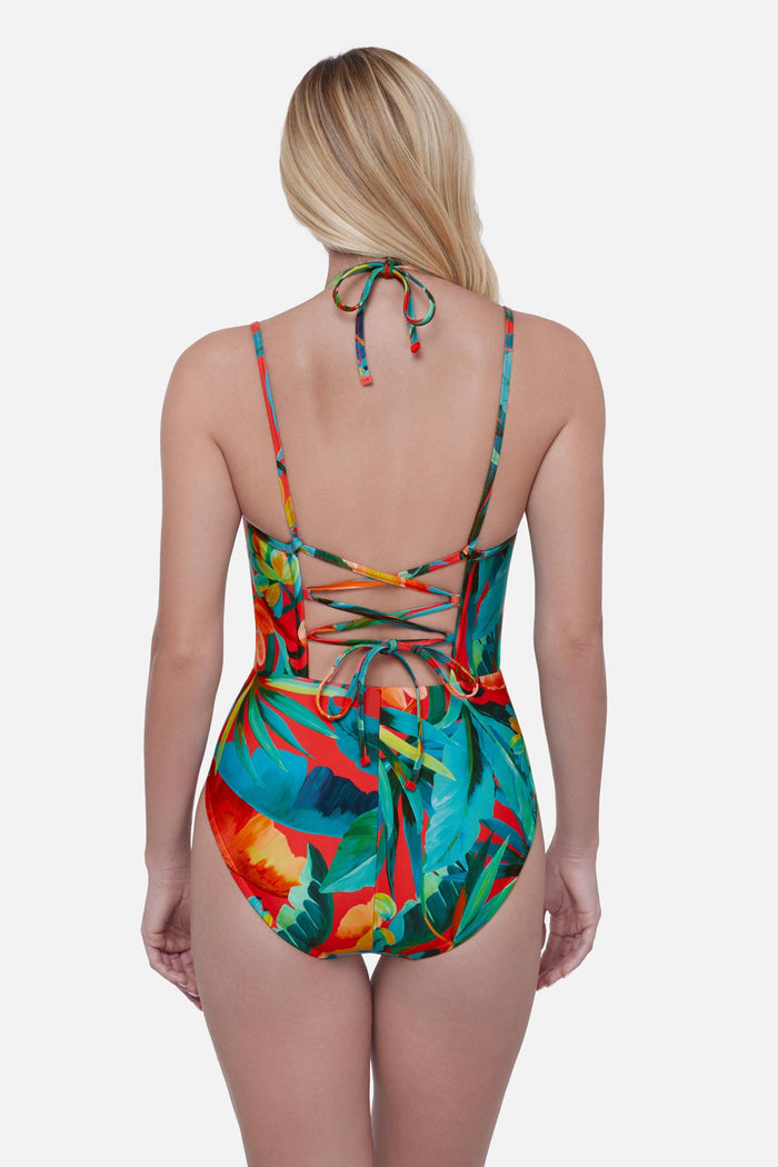 Woman turned away wearing a bright multicolored palm leaf printed one-piece swimsuit with double straps
