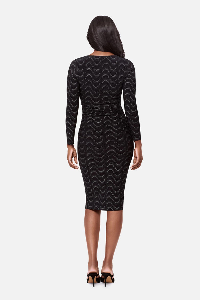 Woman faced away wearing a black long sleeve dress with a glittery wave pattern