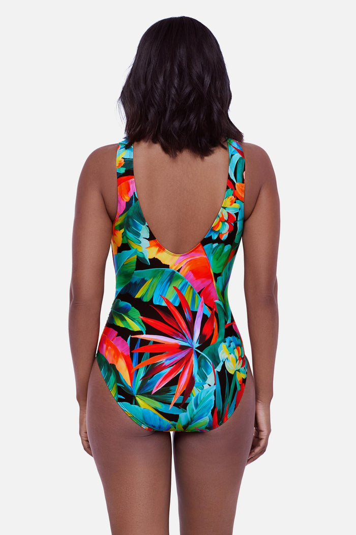 Woman turned away wearing a bright multicolored palm leaf print one-piece swimsuit